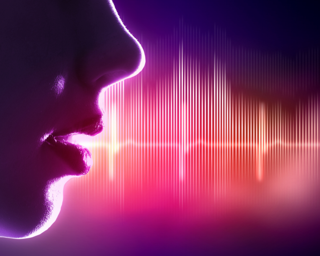 Close-up profile of a face with lips parted as if speaking, with colorful digital sound wave visualization projecting from the mouth. The image features vibrant purple, pink, and orange hues against a dark background with vertical frequency bars.