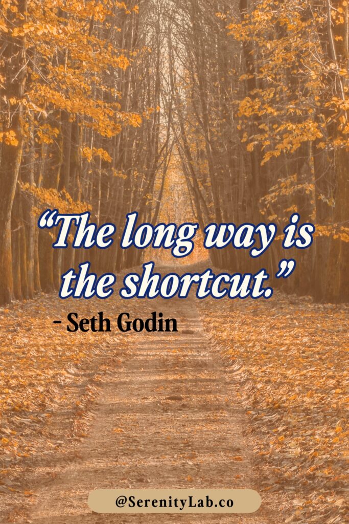 A forest path covered in golden autumn leaves stretching into the distance, with "The long way is the shortcut." – Seth Godin.